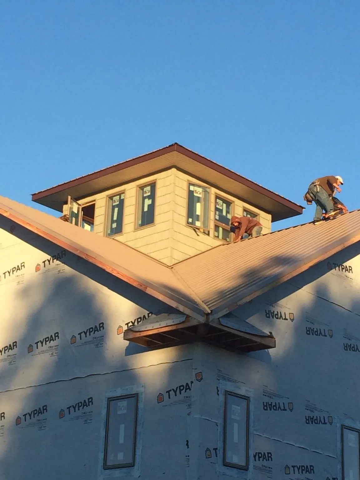 Roofers working around a rooftop cupola on a new metal roof at sunset — Roof Waterproofing in Rhinelander by Roofing Brothers